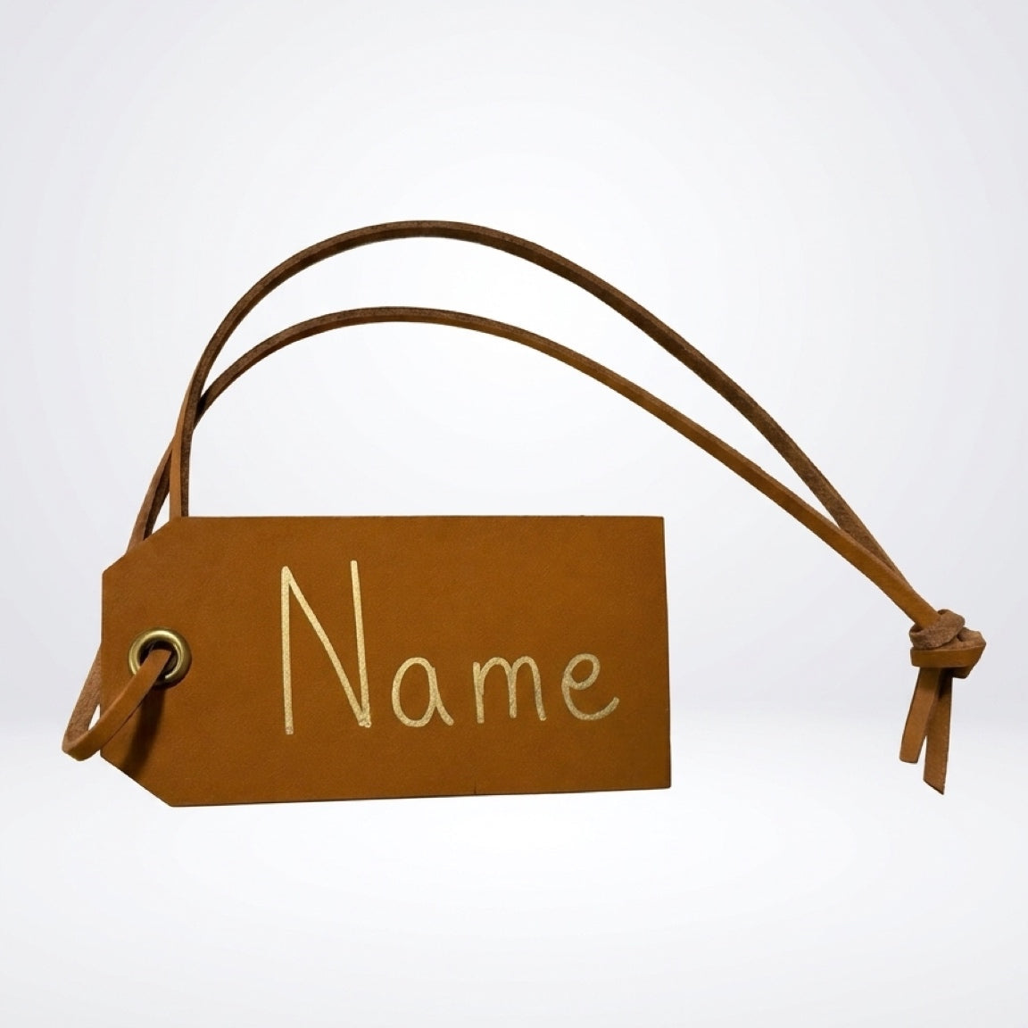 A rectangular brown faux leather luggage tag with a matching leather loop and tie, featuring the word 'Name' printed in white script on the front, set against a light gray gradient background.